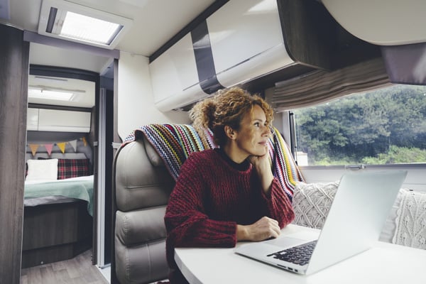 woman sitting near the window of an RV working on her laptop